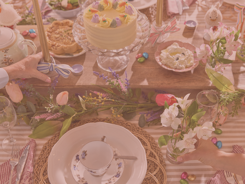 Decorated table with Easter-themed items including a cake, eggs, and flowers.