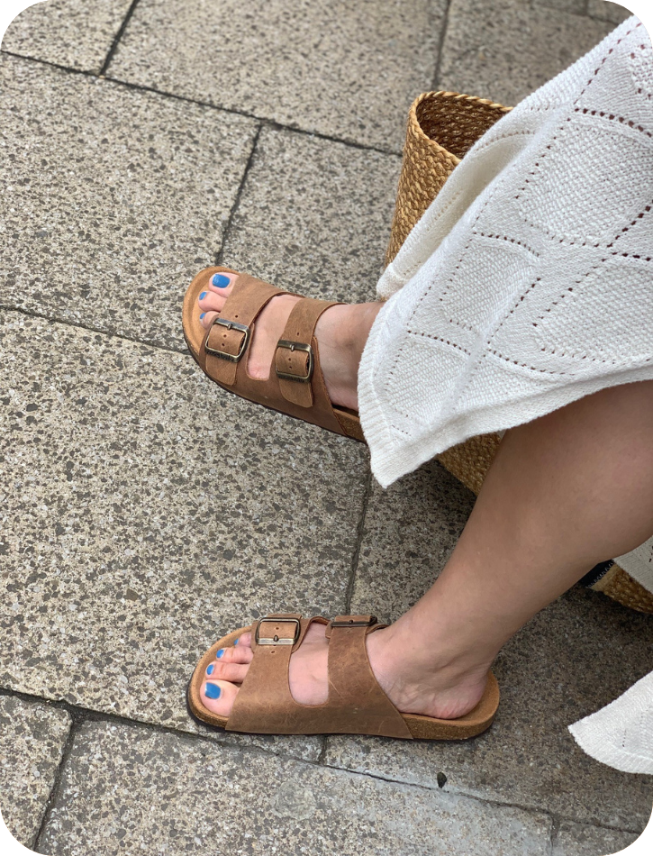 Person wearing brown sandals on a stone pavement